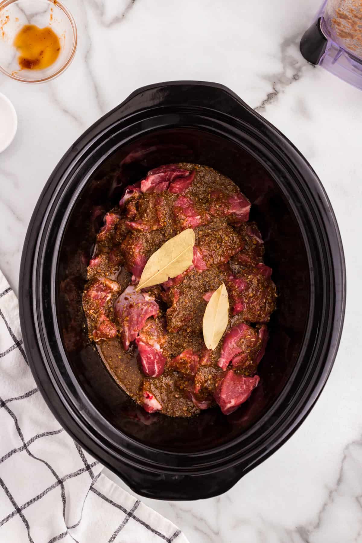 Topping Barbacoa Beef mixture with bay leaves in crock pot