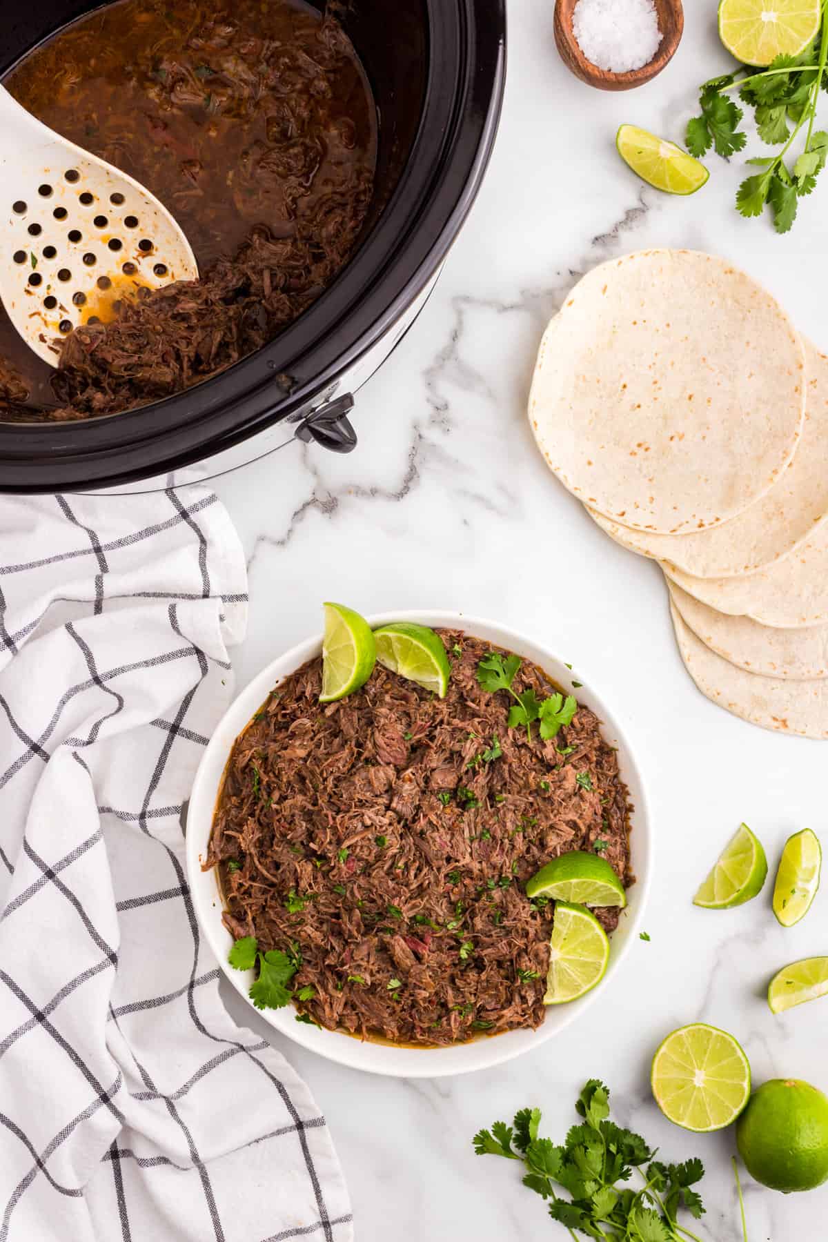 Beef Barbacoa in serving bowl topped with fixings