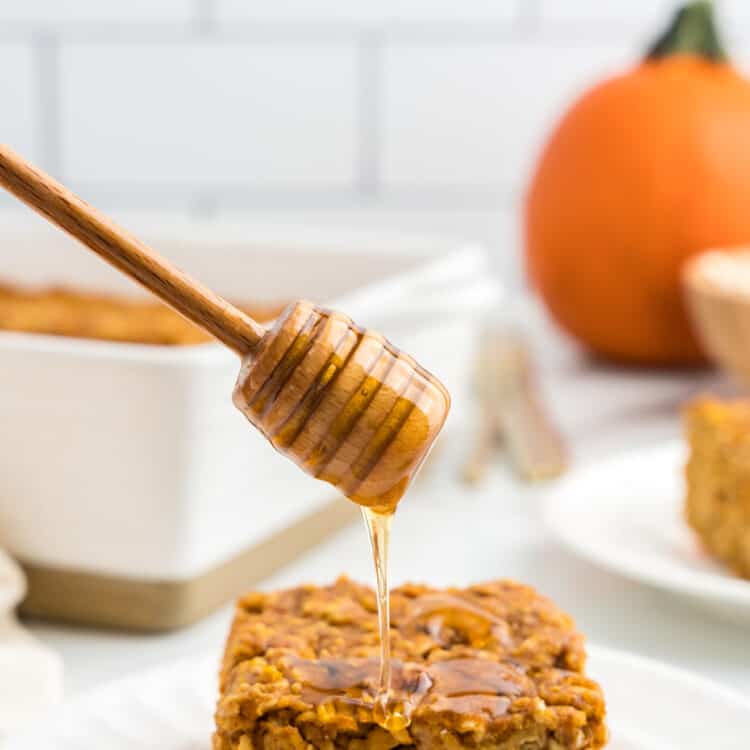 Pumpkin Baked Oatmeal square on plate being drizzled with honey