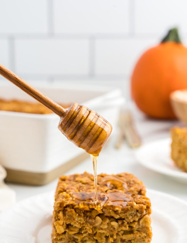 Pumpkin Baked Oatmeal square on plate being drizzled with honey