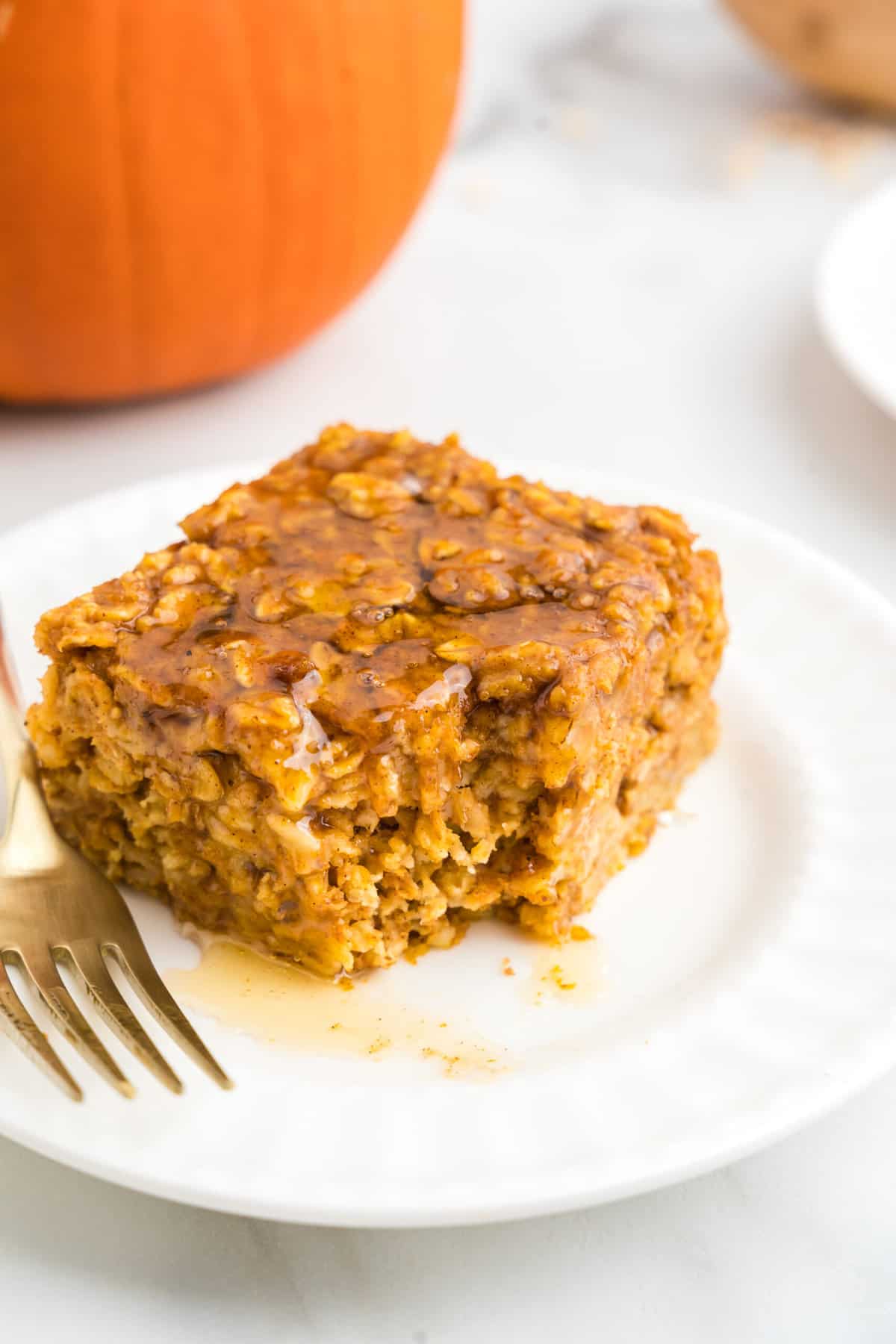 Square Pumpkin Baked Oatmeal piece on plate drizzled with honey with one bite taken