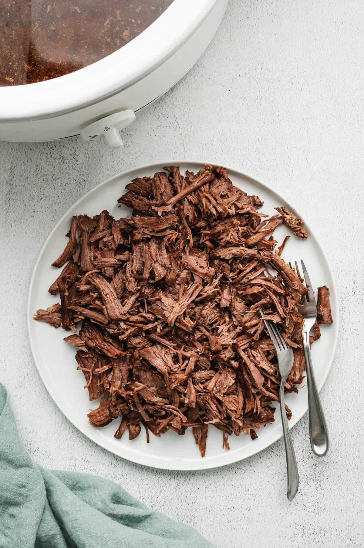 Shredding seasoned beef on plate with fork for French Drip