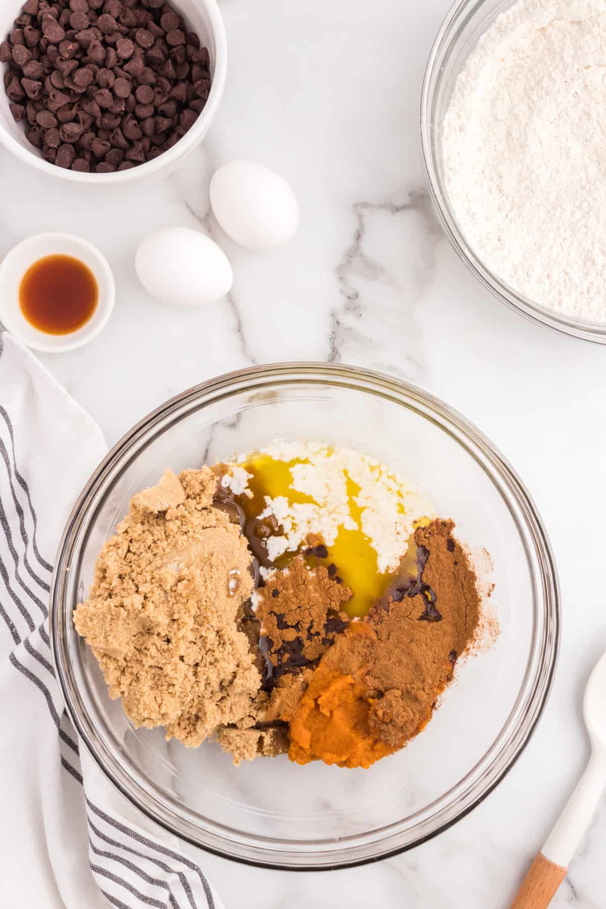 Adding in pumpkin puree and other ingriendets in mixing bowl for Easy Pumpkin Chocolate Chip Cookies