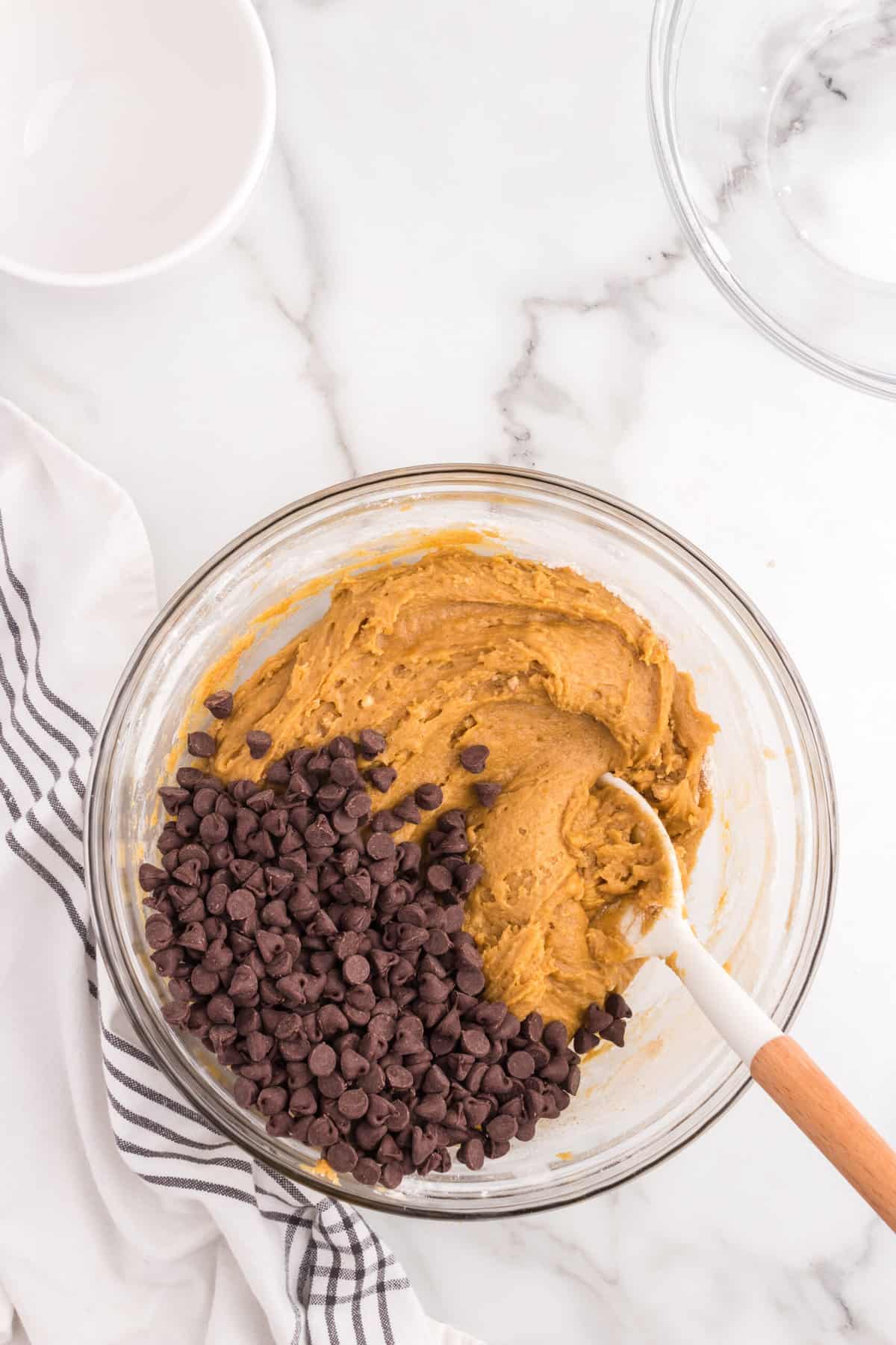 Folding in chocolate chips in to Soft Pumpkin Chocolate Chip Cookies batter in mixing bowl