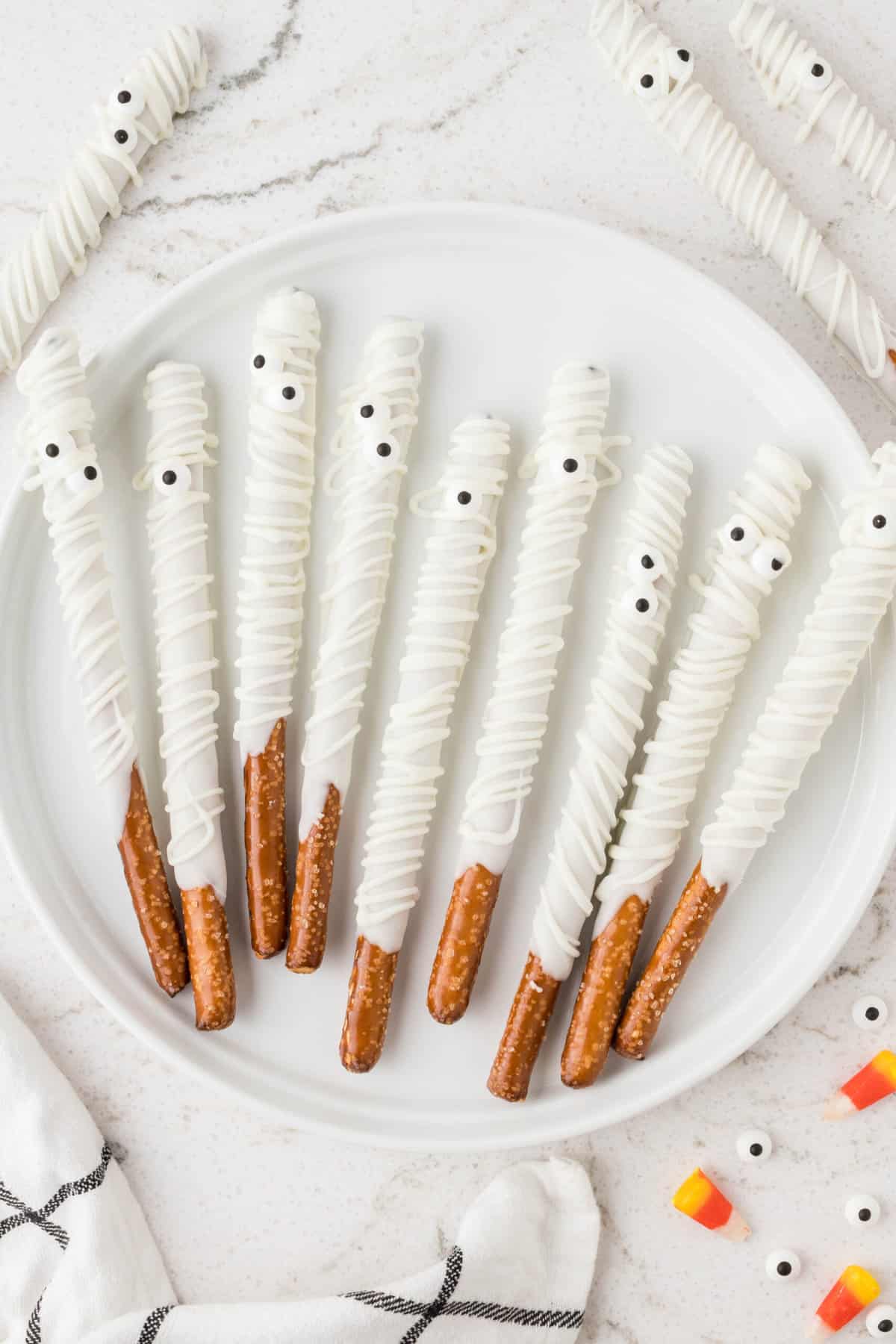A White plate displaying mummy pretzel rods.