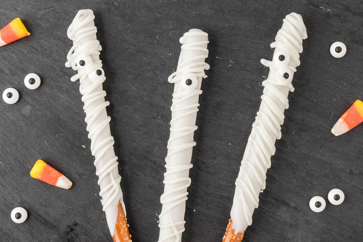 Mummy Pretzel Rods displayed on a Black sheet of paper.