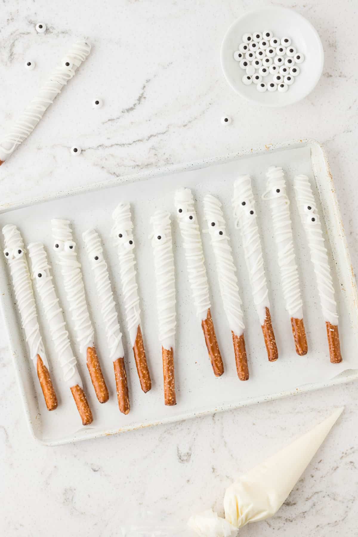 Once all of the Pretzel Rods are dipped, cut and end of the piping bag to drizzle almond bark back and forth to make mummy like lines on the pretzel rods.