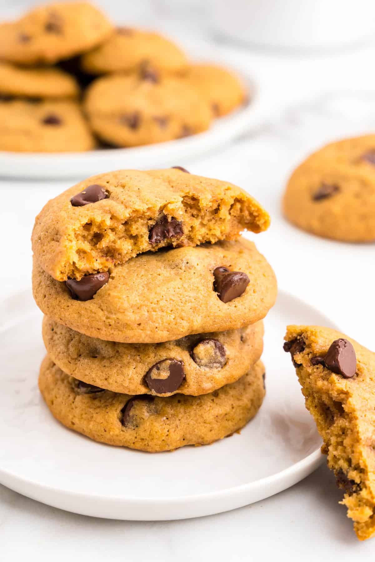 Soft Pumpkin Chocolate Chip Cookies Stacked on Plate with one bite taken