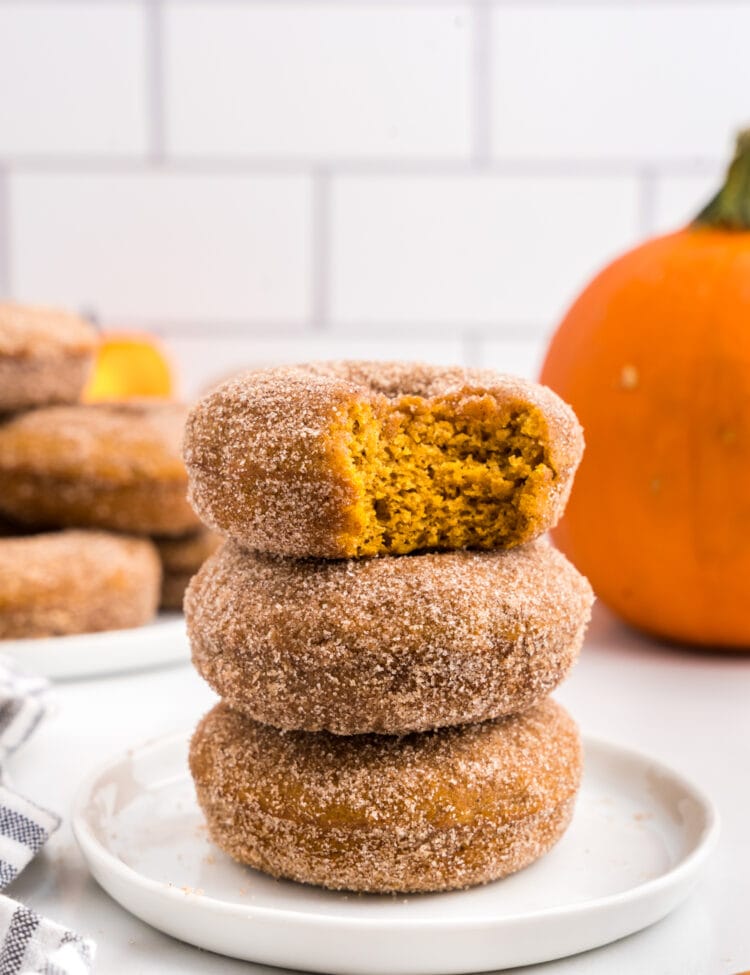 Best Pumpkin Donuts stacked on plate with one bite taken