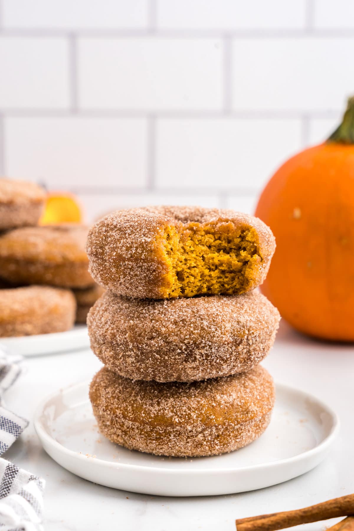 Best Pumpkin Donuts stacked on plate with one bite taken