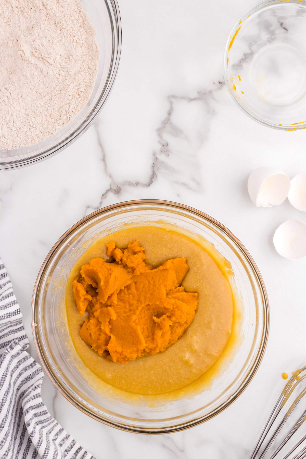 Adding pumpkin puree to mixture in mixing bowl for Pumpkin Donuts