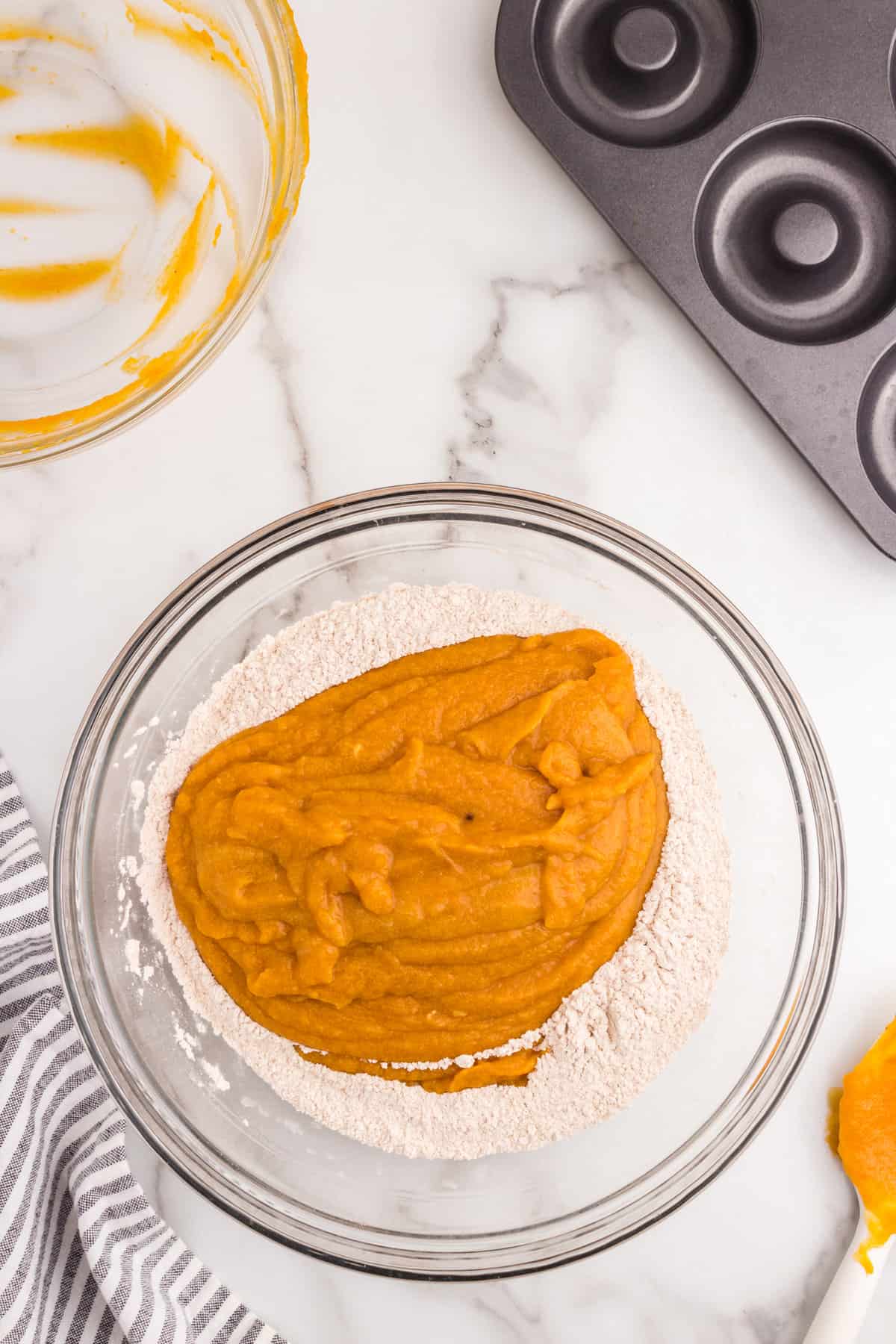 Folding wet mixture into dry mixture in bowl for Pumpkin Donuts recipe