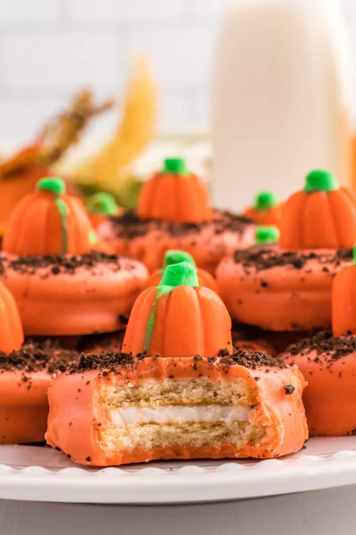 a Plate full of Pumpkin cookies with the front cookie having a bite taken out of it.