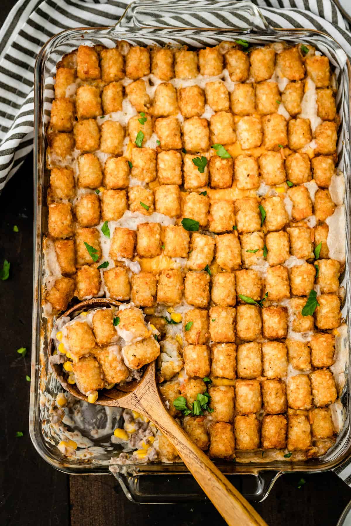 Tator Tot Hotdish just out of the oven in baking dish with wooden sppon