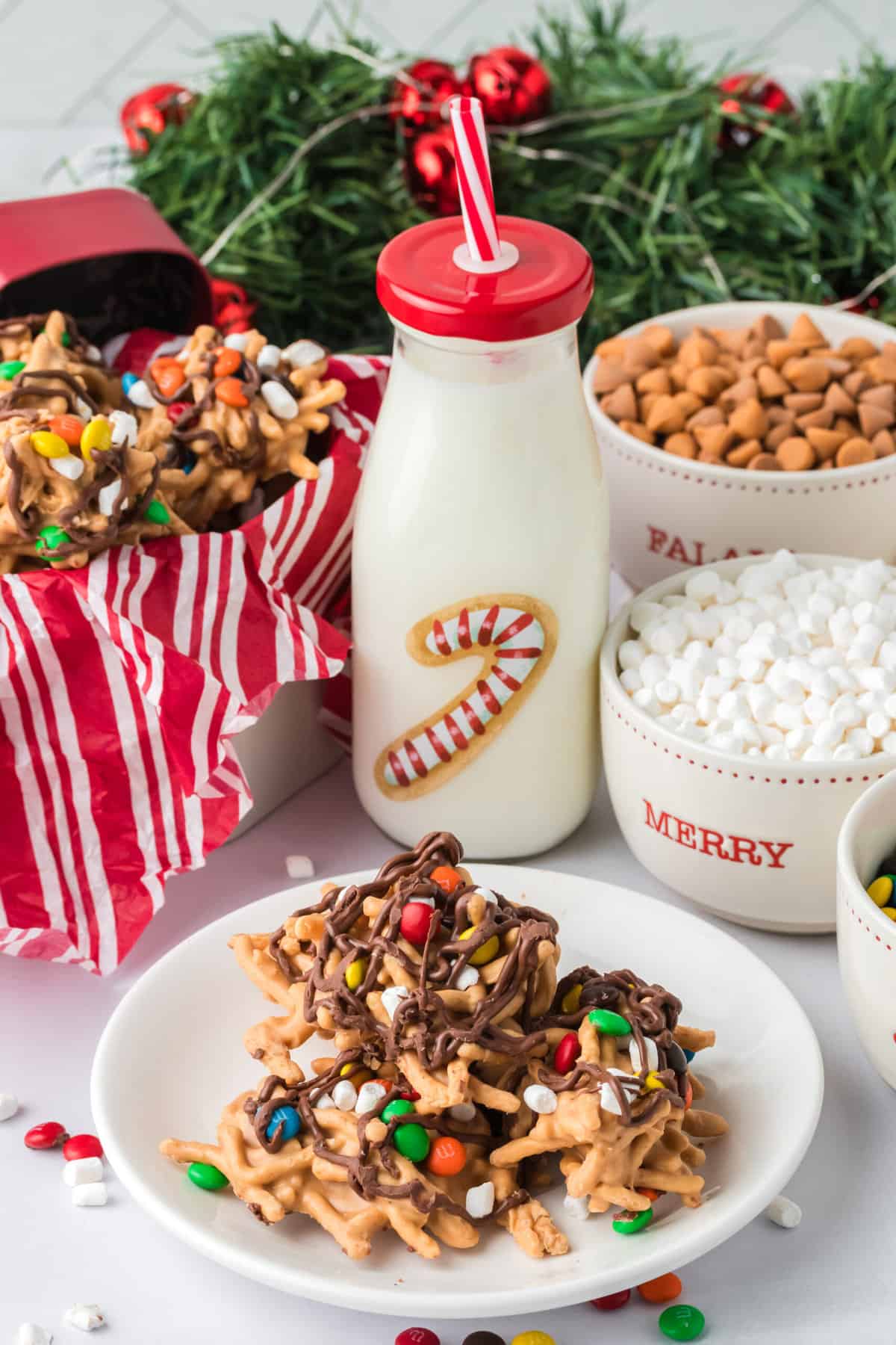 Buddy the elf cookies displayed on a white plate with milk and chocolate chips in the background.