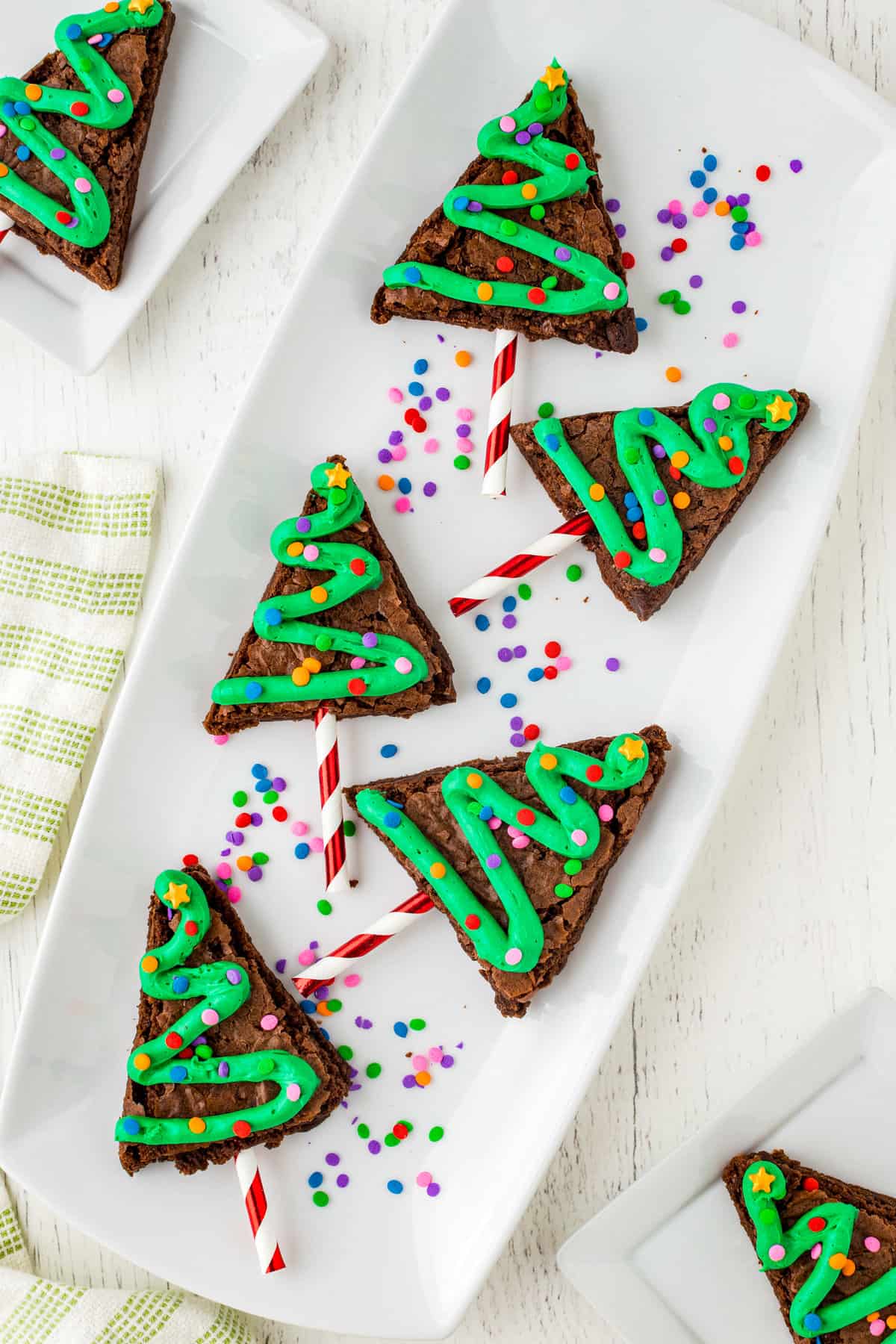 Christmas Tree Brownies displayed on a White plate with sprinkles.