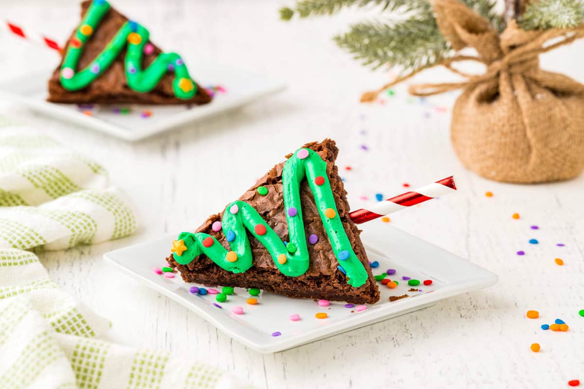 Two Christmas Tree Brownies Sitting on White Plates with Sprinkles