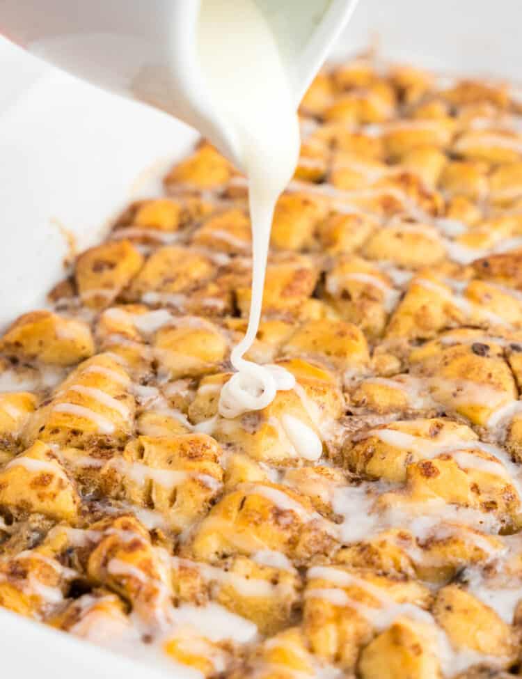 Pouring frosting over Cinnamon Roll Casserole in baking dish