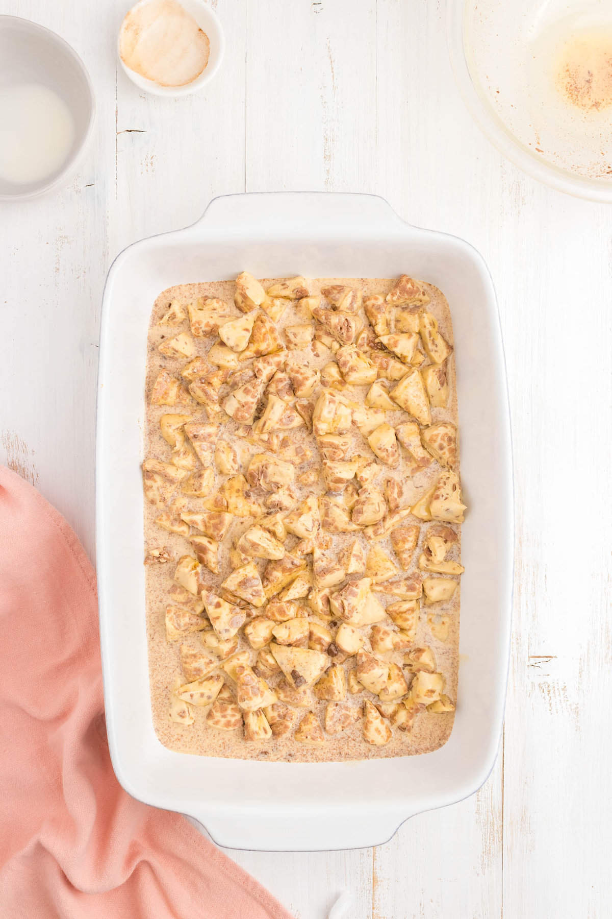 Cinnamon roll pieces covered in egg mixutre in baking dish for Cinnamon Roll Casserole Recipe