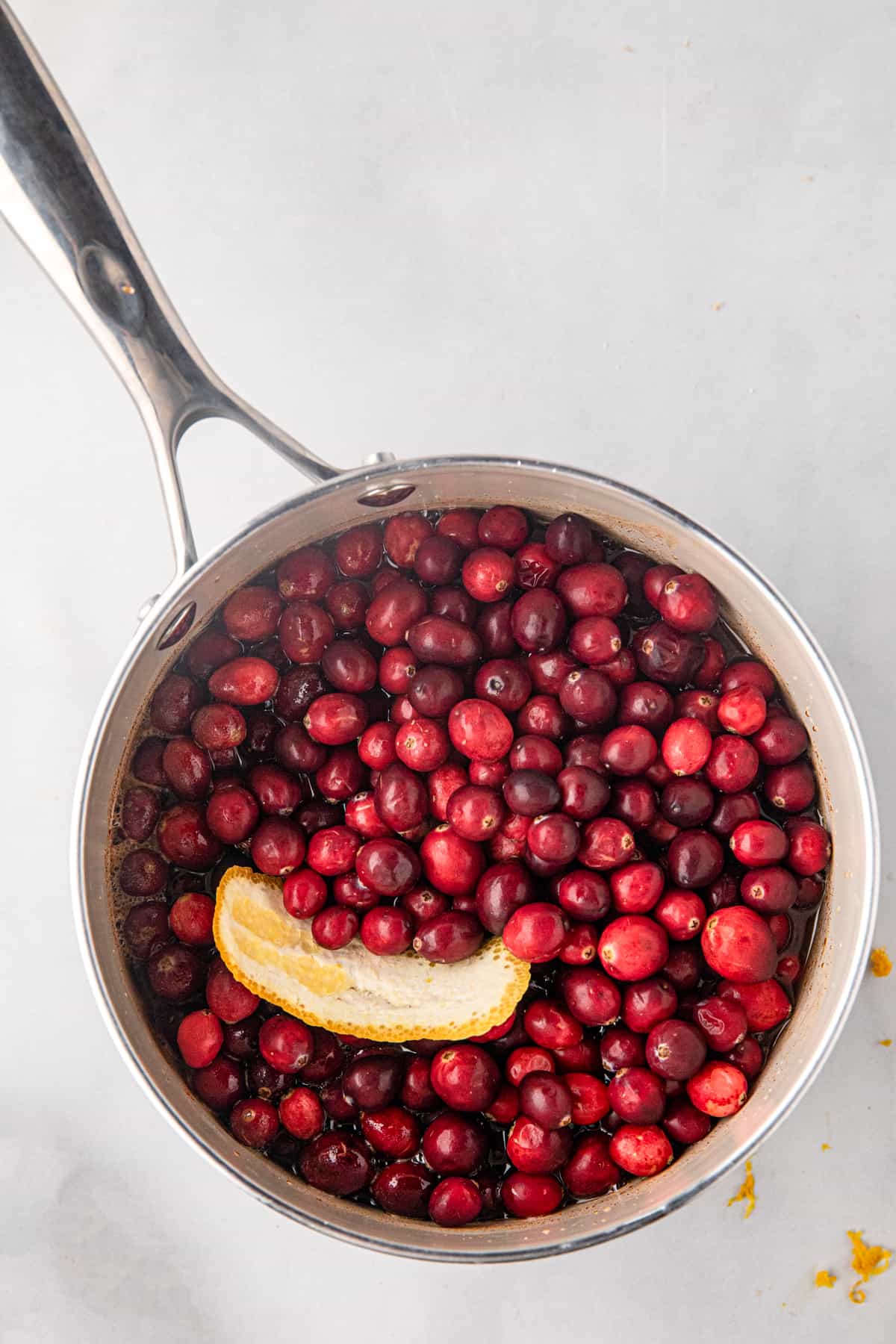 Cranberries in saucepan with orange peel