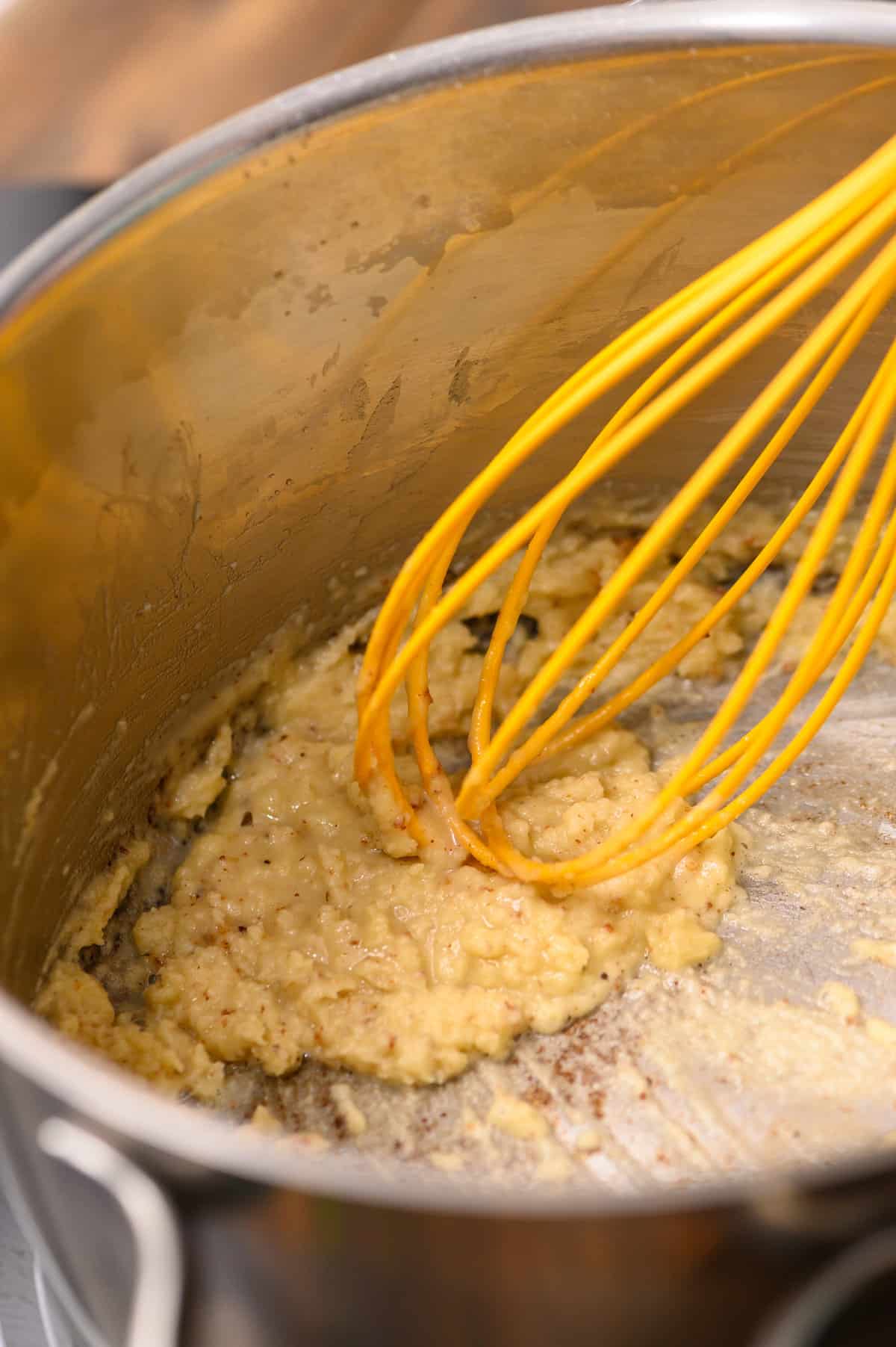 Whisking together butter, flour, and seasonings for Creamed Peas recipe in saucepan