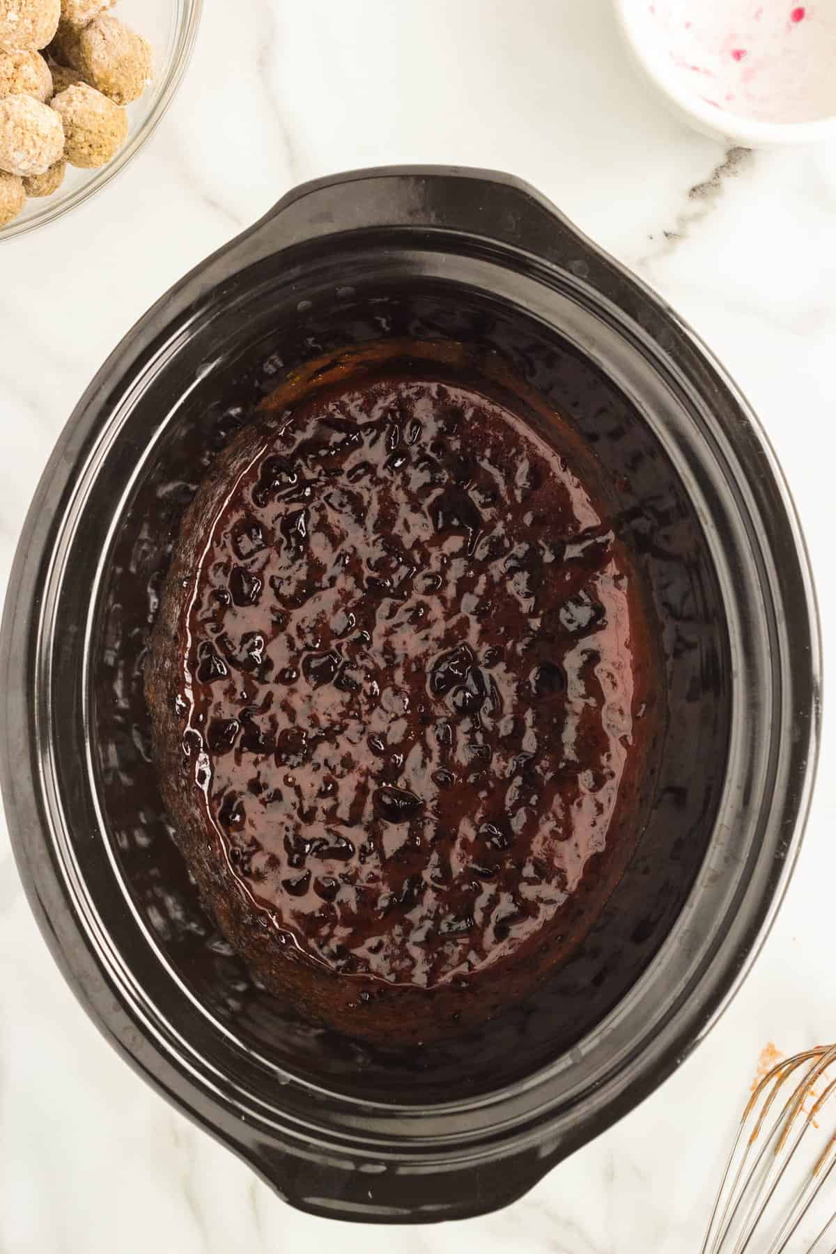 Whisked together grape jelly and chili sauce in crock pot for Grape Jelly Meatballs