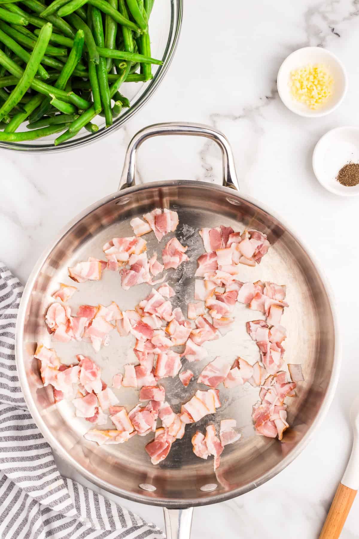 Uncooked bacon pieces in stovetop skillet for Green Beans with Bacon recipe