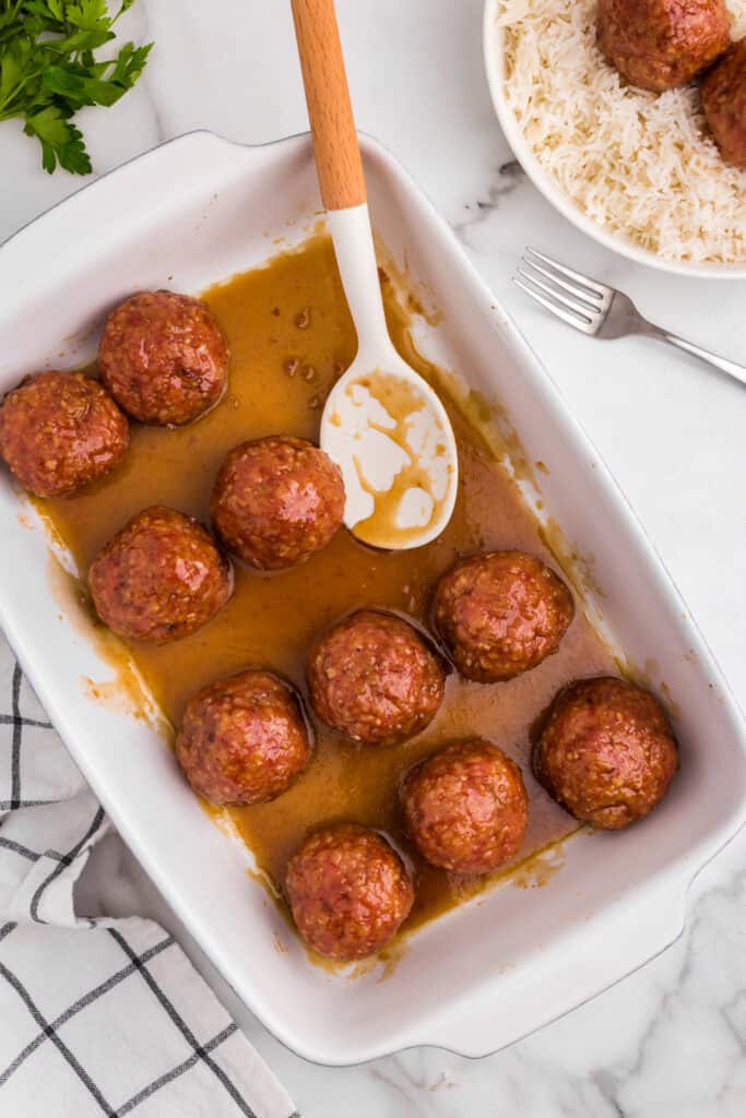 Scooping Ham Balls from baking dish with serving spoon