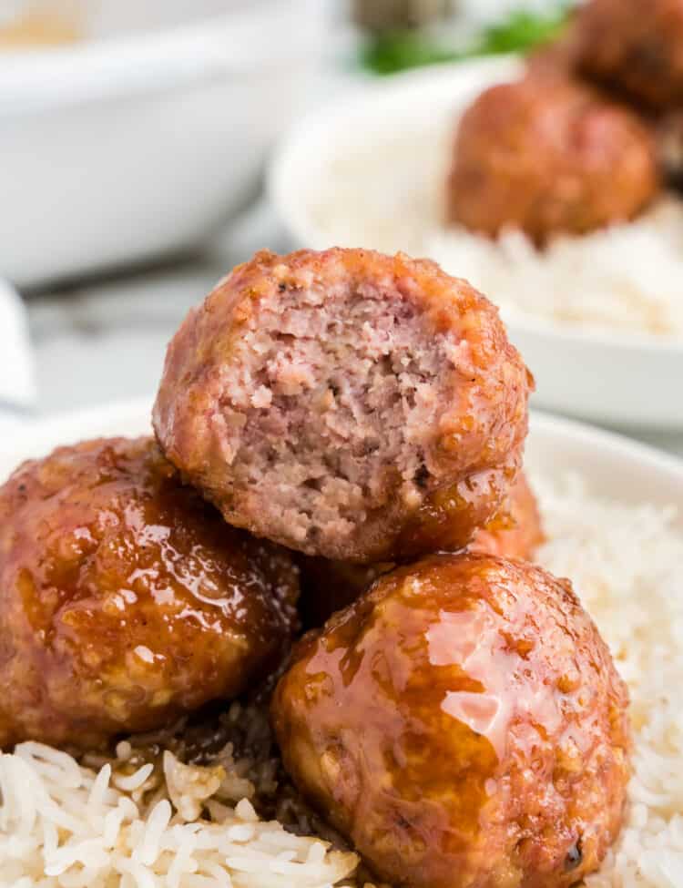 Ham balls on a bed of rice in a serving bowl with one bite taken