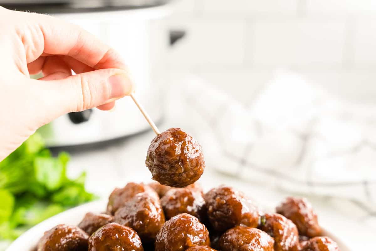 Grape Jelly Meatballs in serving dish and using tootpick for the first bite