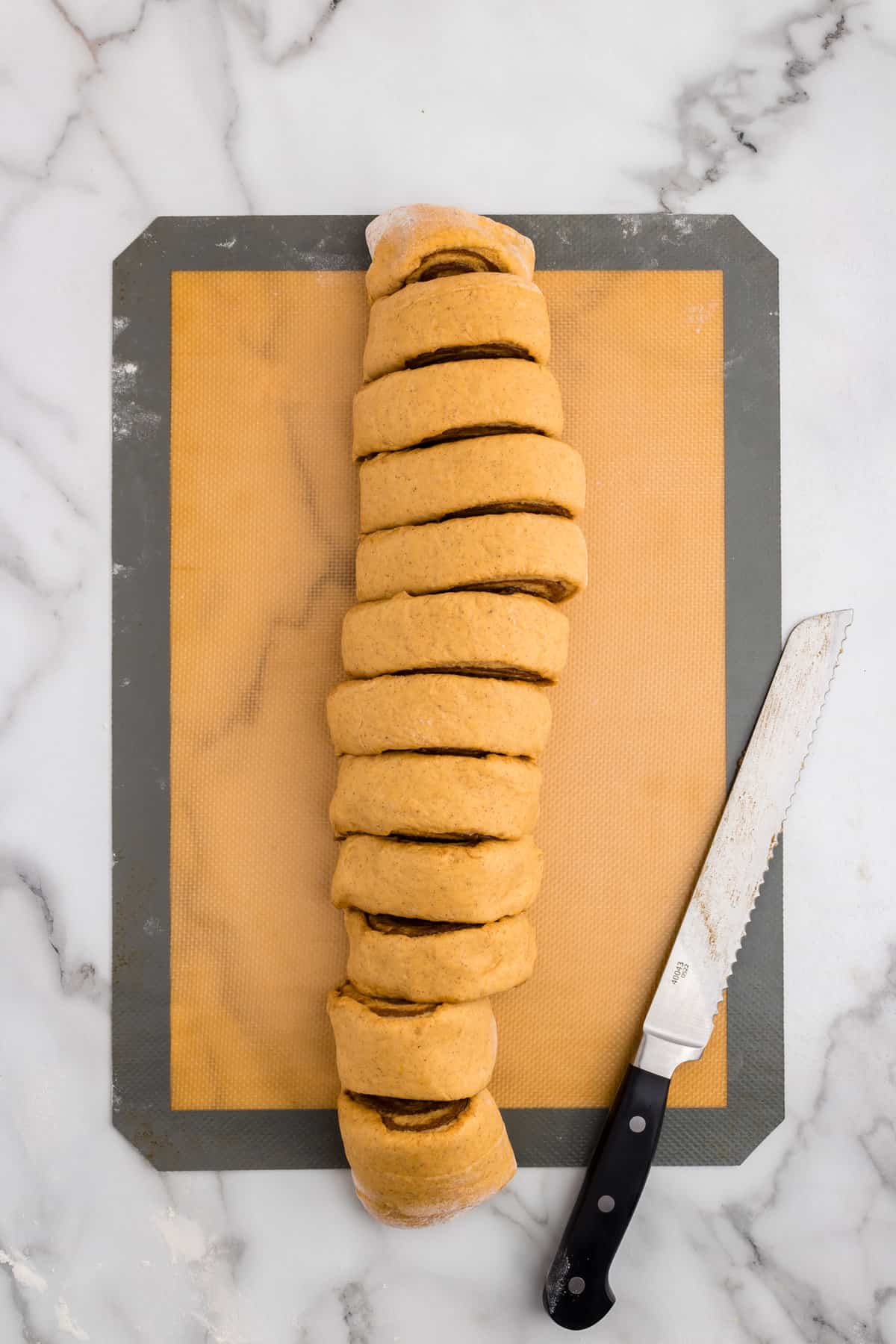 Rolled up Pumpkin Cinnamon Rolls dough with slices on cookie sheet