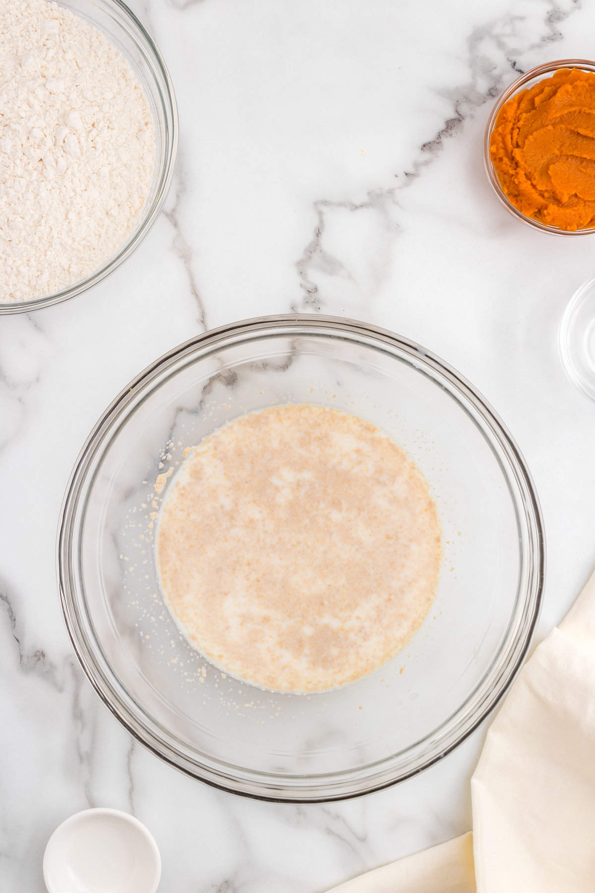 Warm milk and active dry yeast in glass mixing bowl for Pumpkin Cinnamon Rolls recipe