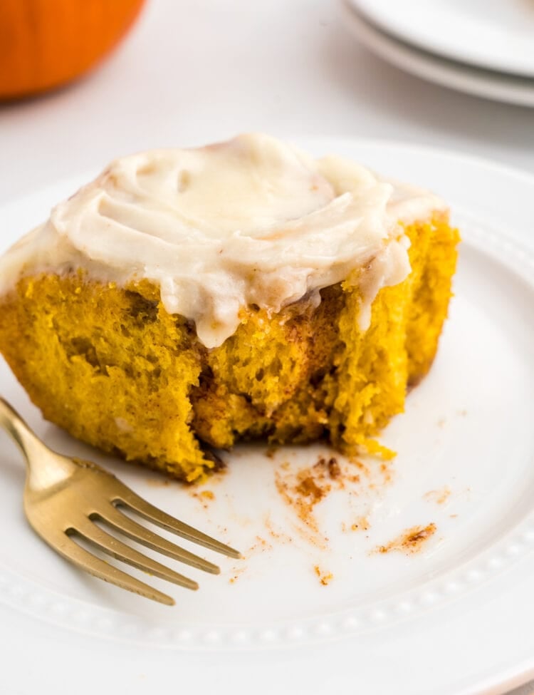 Pumpkin Cinnamon Roll on plate with one bite taken and a fork set aside