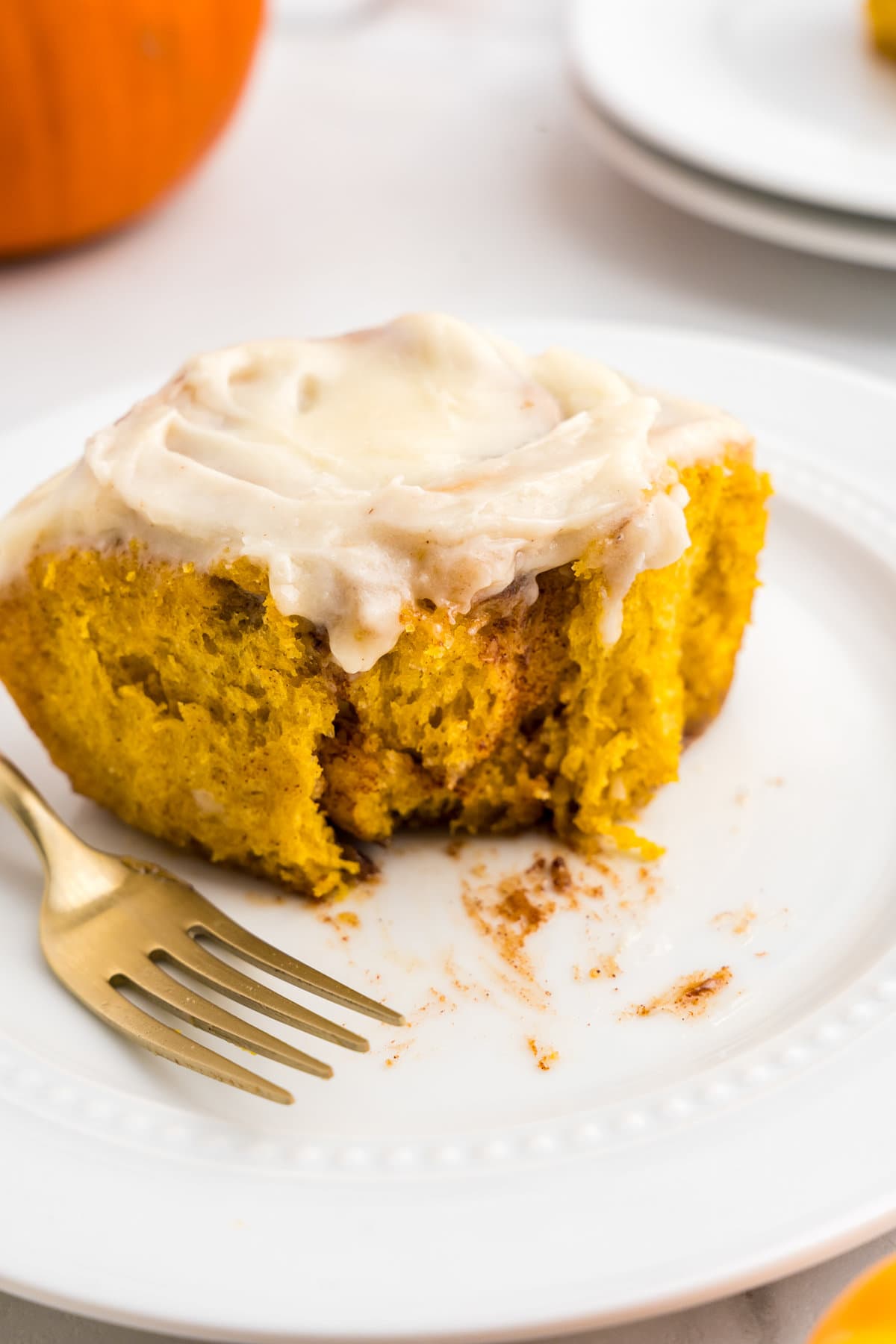 Pumpkin Cinnamon Roll on plate with one bite taken and a fork set aside