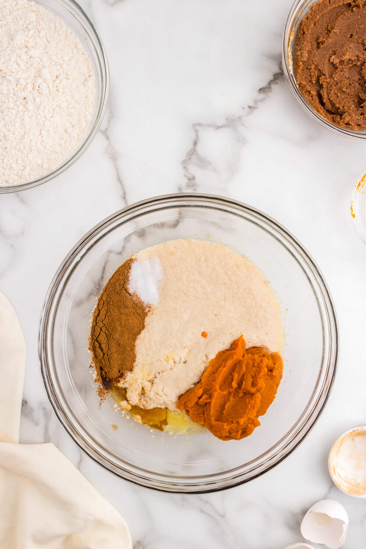 Adding seasonings and pumpkin puree to yeast mixture in glass mixing bowl for Pumpkin Cinnamon Rolls recipe