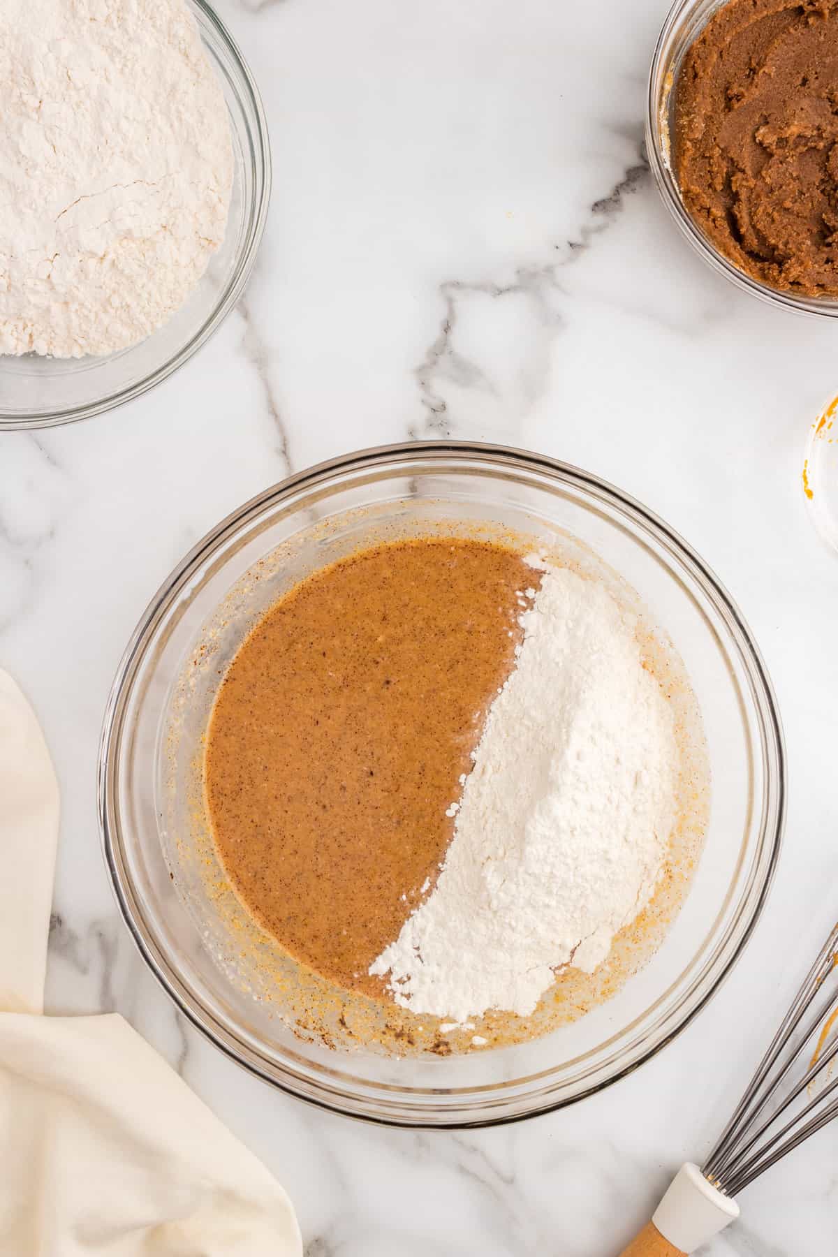 Adding flour to Pumpkin Cinnamon Rolls dough mixture in glass bowl