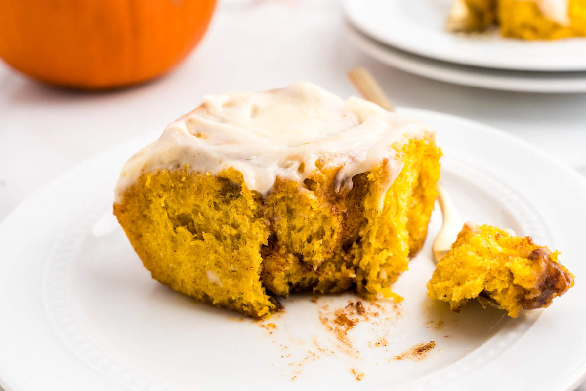 Pumpkin Spice Cinnamon Roll on plate with one bite taken