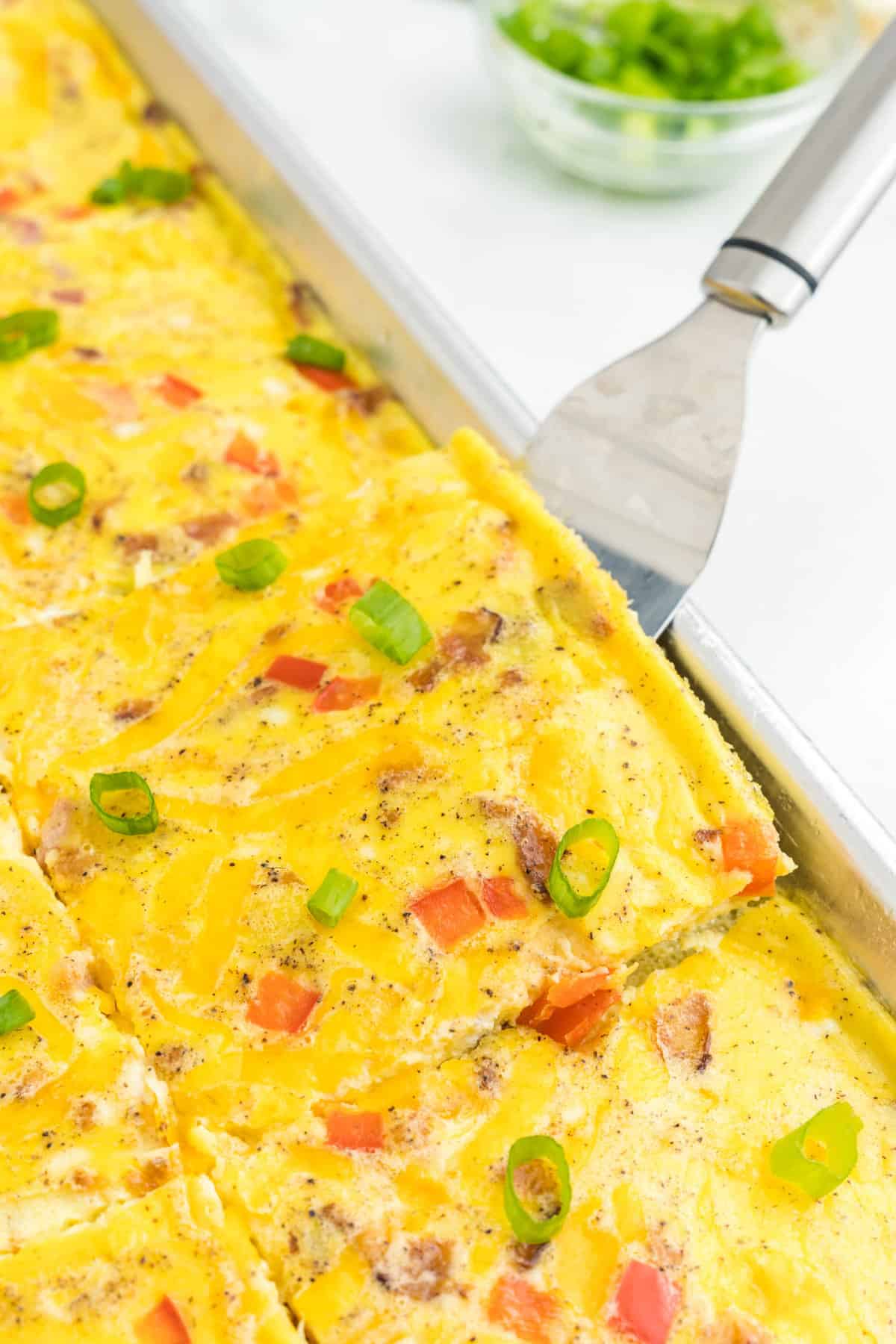 Sheet Pan Eggs cut into square in shallow baking pans with metal spatula