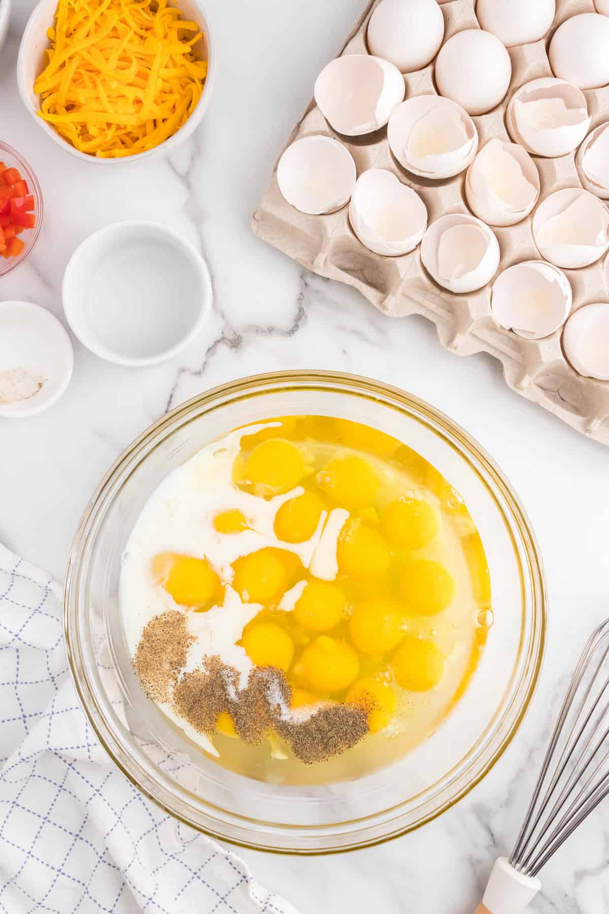 Adding milk and seasoning to eggs in mixing bowl for Sheet Pan Eggs Recipe