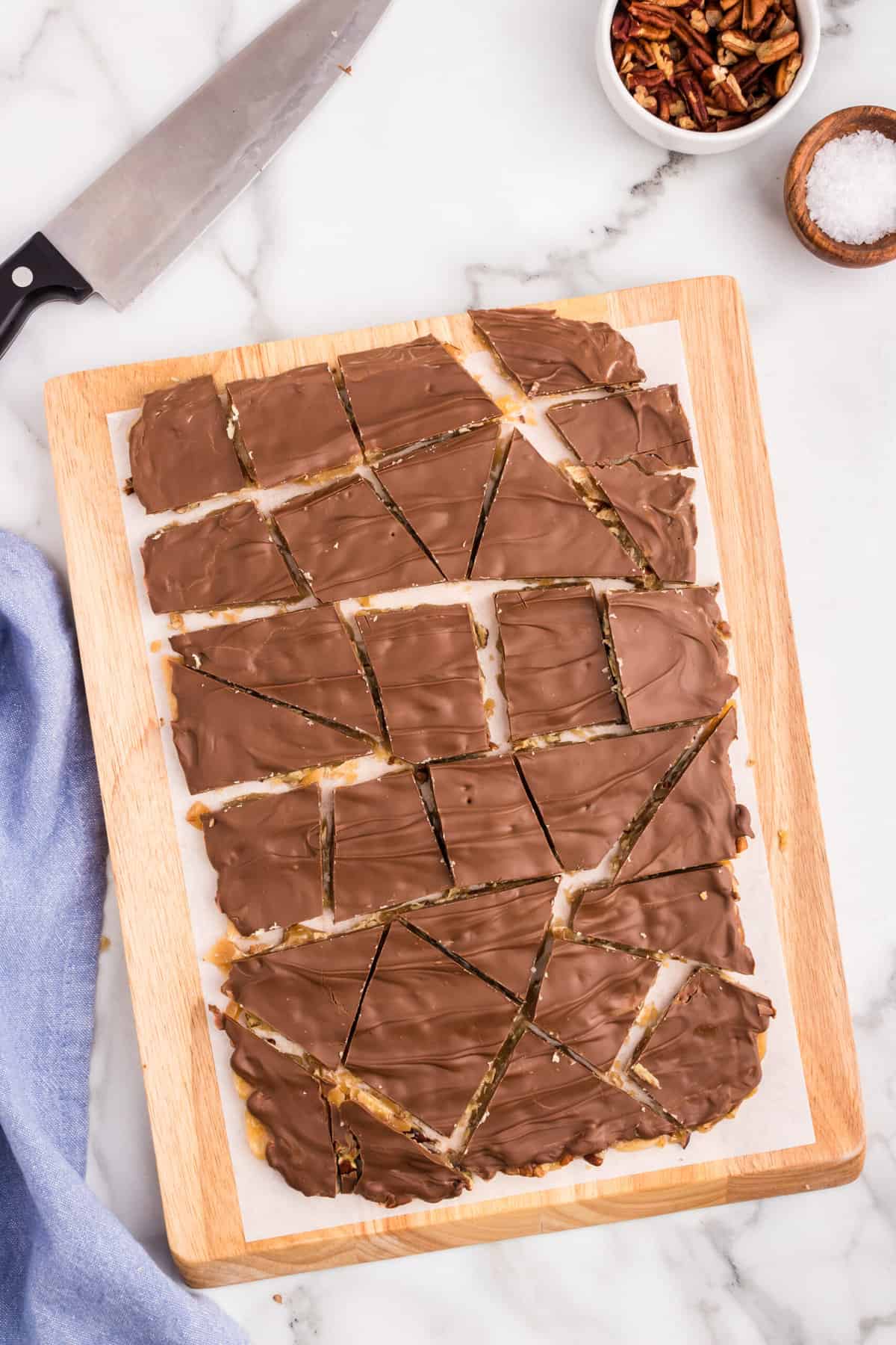 Broken apart Toffee pieces by using a knife on cutting board