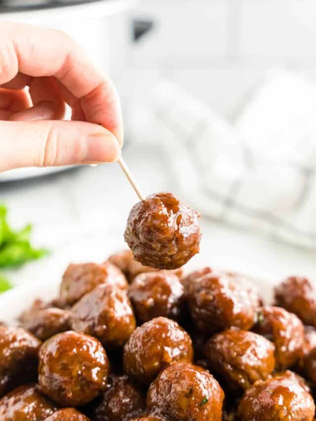 Grape Jelly Meatballs in serving dish and using tootpick for the first bite