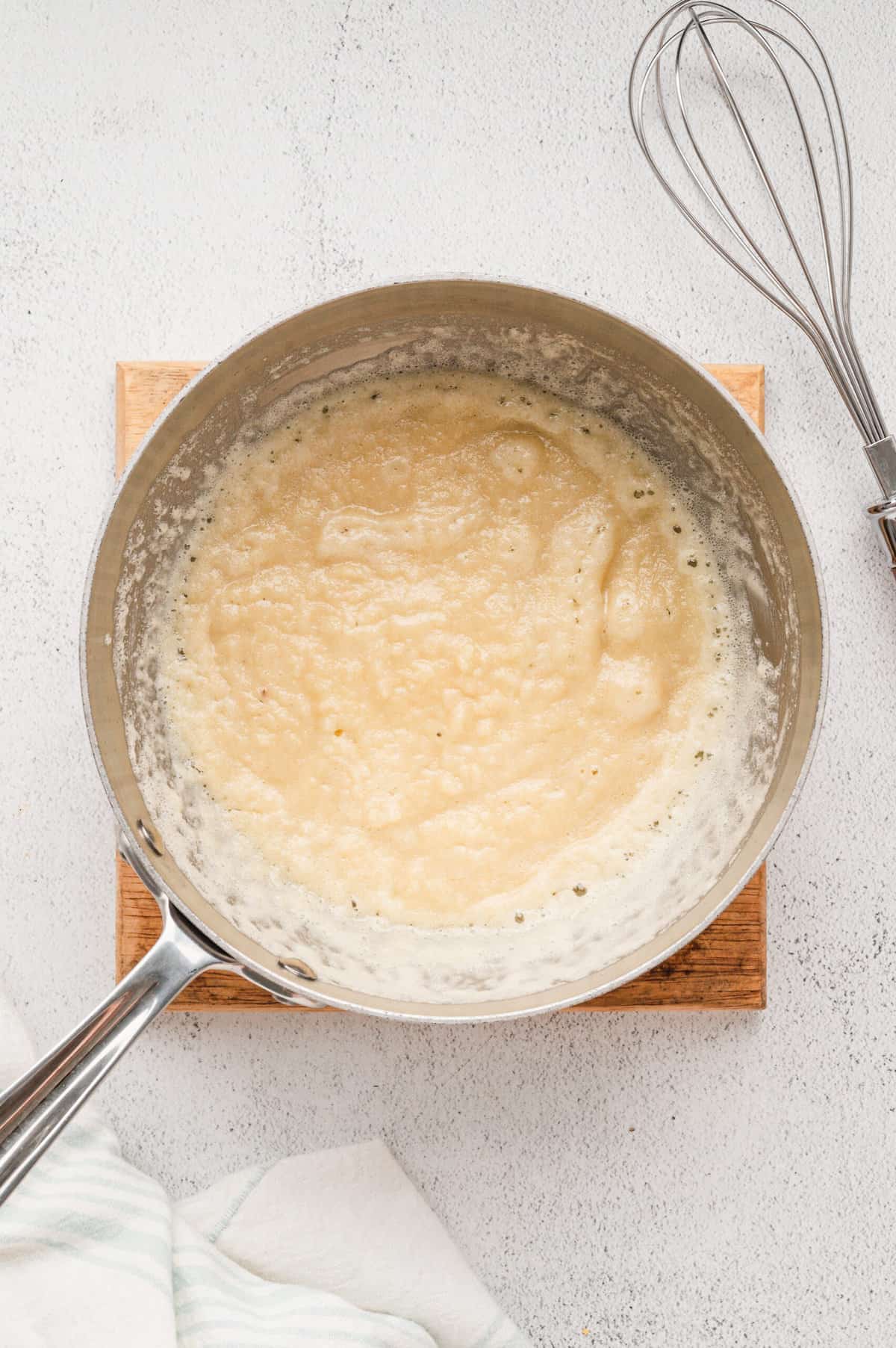 Bringing gravy mixture to a bowl in stovetop sauce pan for Bicuits & Gravy Casserole recipe