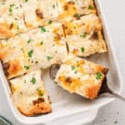 Square image of Biscuits & Gravy Casserole in baking pan cut into squares
