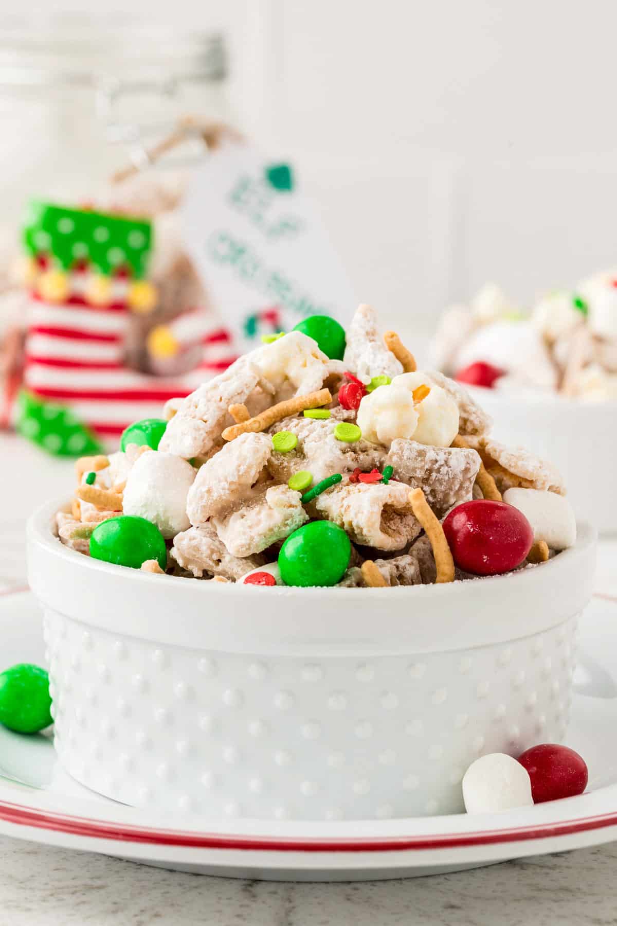 a White Bowl on a White Plate Full of Buddy the Elf Snack Mix with Sprinkles.