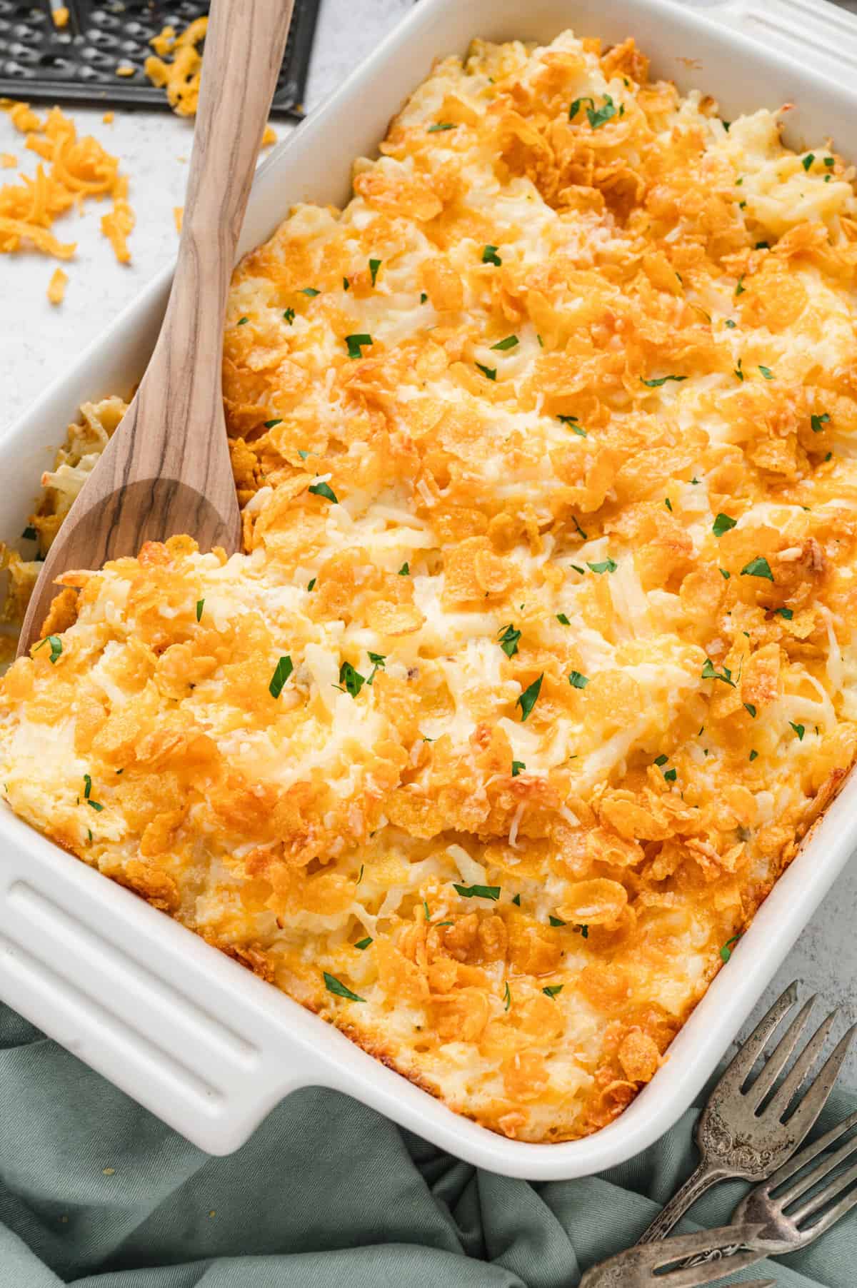 Using a wooden spoon to scoop the first bite of Cheesy Potatoes