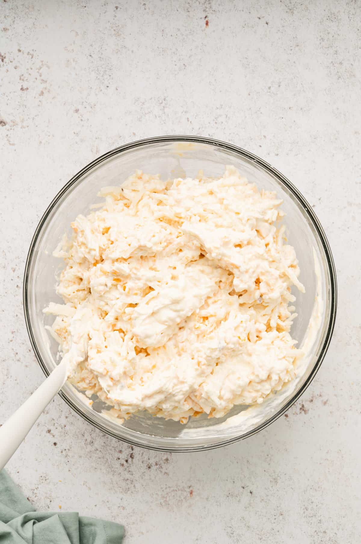 Adding shredded frozen hash browns to ingredient mixture for Cheesy Hashbrown Potatoes recipe