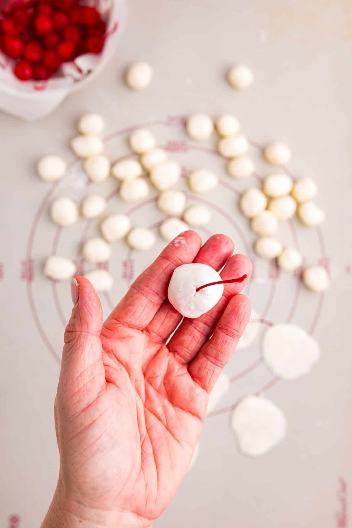 Wrapping dough mixture around cherries with hands