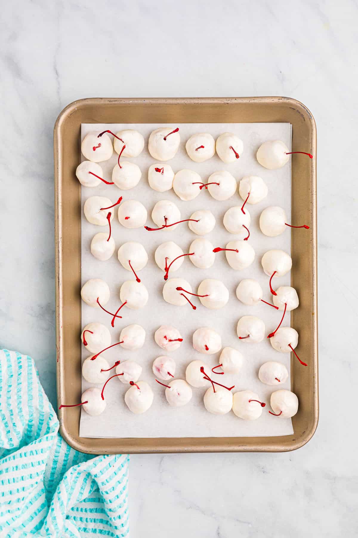 Covered cherries on parchment lined baking sheet for Chocolate Covered Cherries recipe