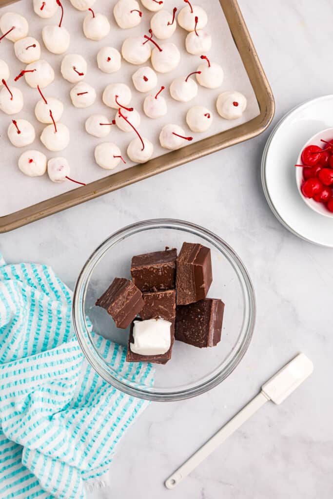 Chocolate almond bark broken into chunks with shortening in small glass mixing bowl for Chocolate Covered Cherries