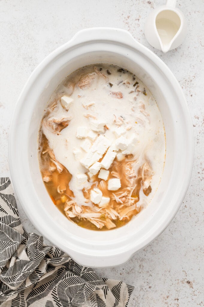 Adding half and half and cream cheese cubes to Crock Pot White Chicken Chili recipe